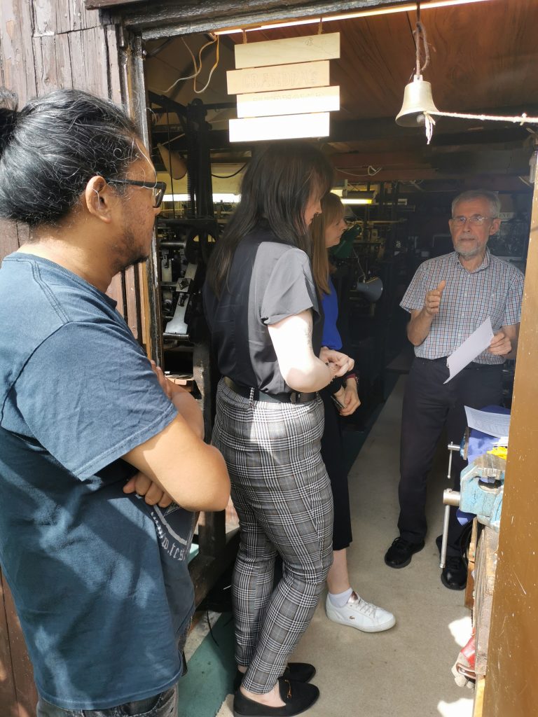 University of Derby staff and students listening to Martin Green explaining the history of his workshop.